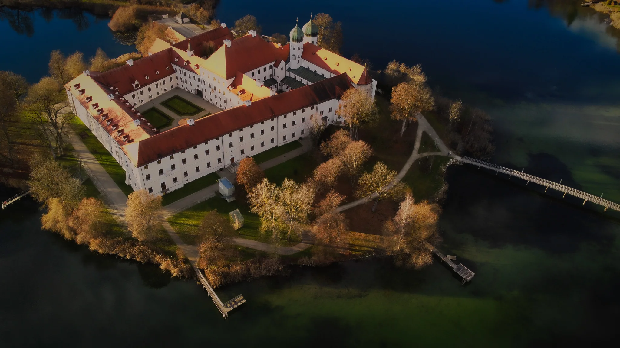 Kloster Seeon aus der Luft, umgeben von Wasser und herbstlicher Landschaft