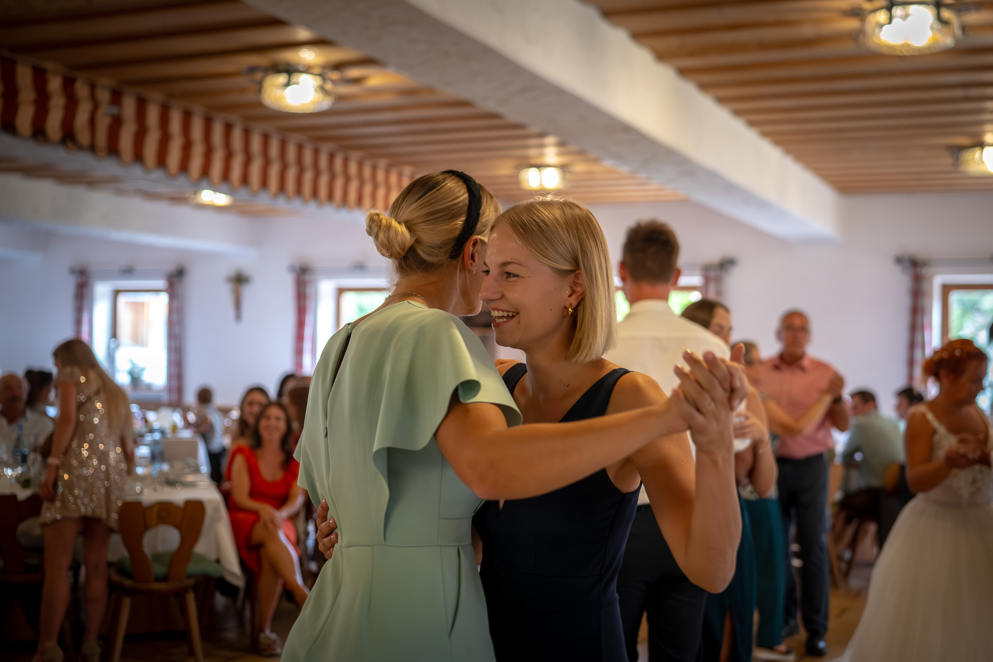 Zwei Hochzeitsgäste lachen und tanzen ausgelassen miteinander.