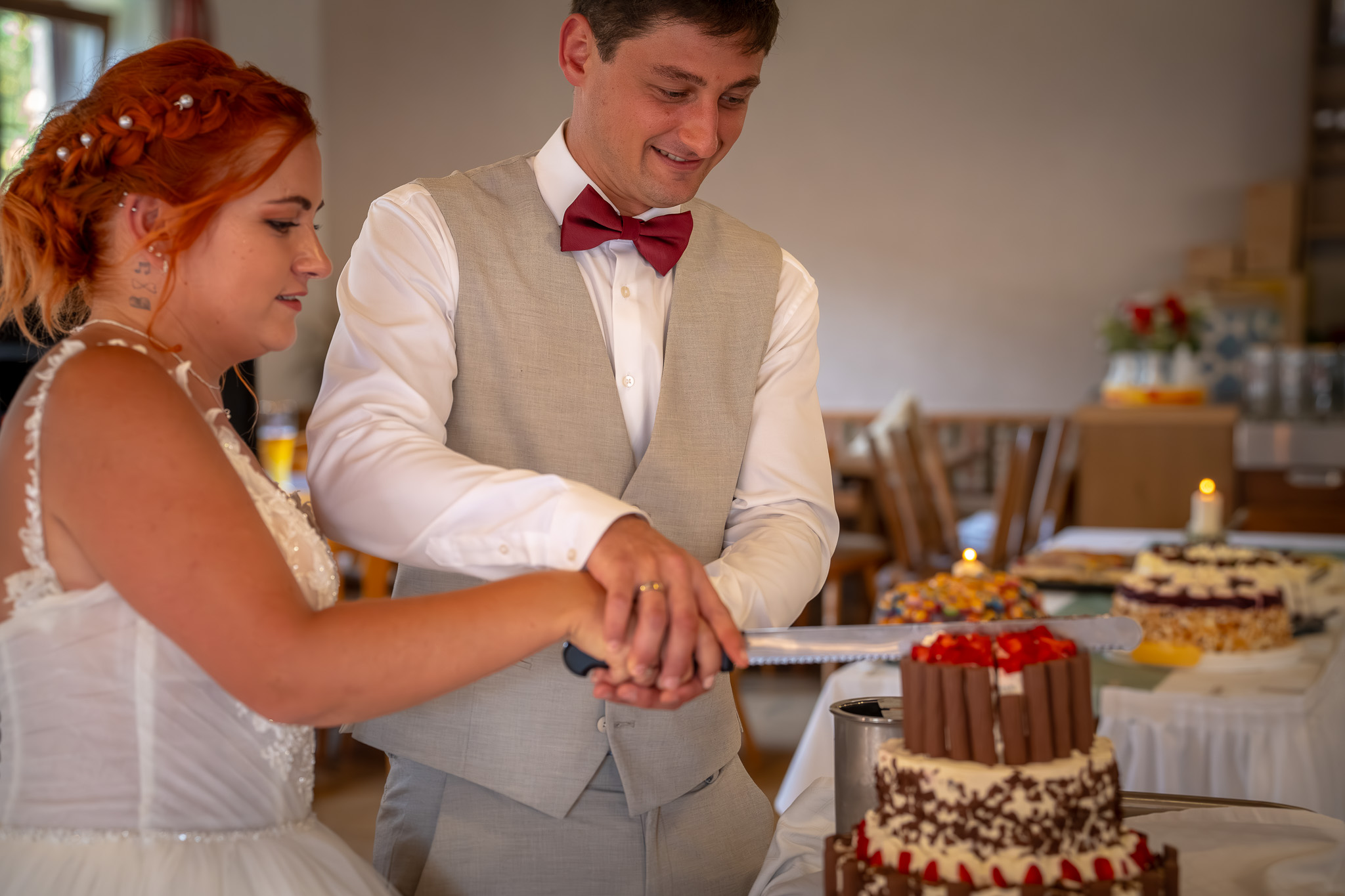 Braut und Bräutigam schneiden gemeinsam ihre Hochzeitstorte an.