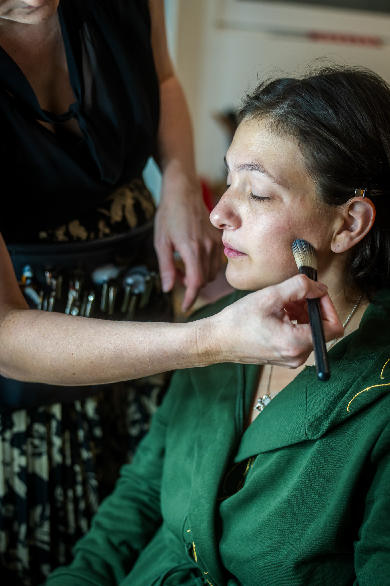 Getting Ready der Braut: Die Stylistin trägt am frühen Morgen sorgfältig das Braut-Make-up auf.