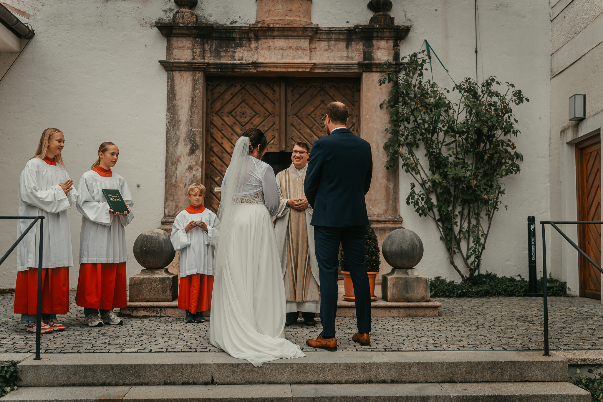 Der Pfarrer begrüßt das Brautpaar vor dem festlich geschmückten Kloster Seeon.