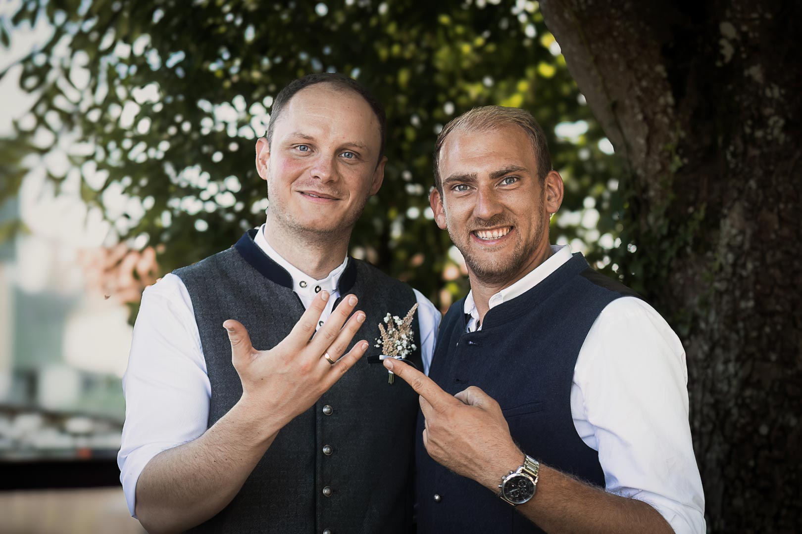 Bräutigam und Trauzeuge mit Eheringen – echte Hochzeitsmomente | Lindl Photography Bräutigam und Trauzeuge zeigen stolz ihre Eheringe und lachen in die Kamera.