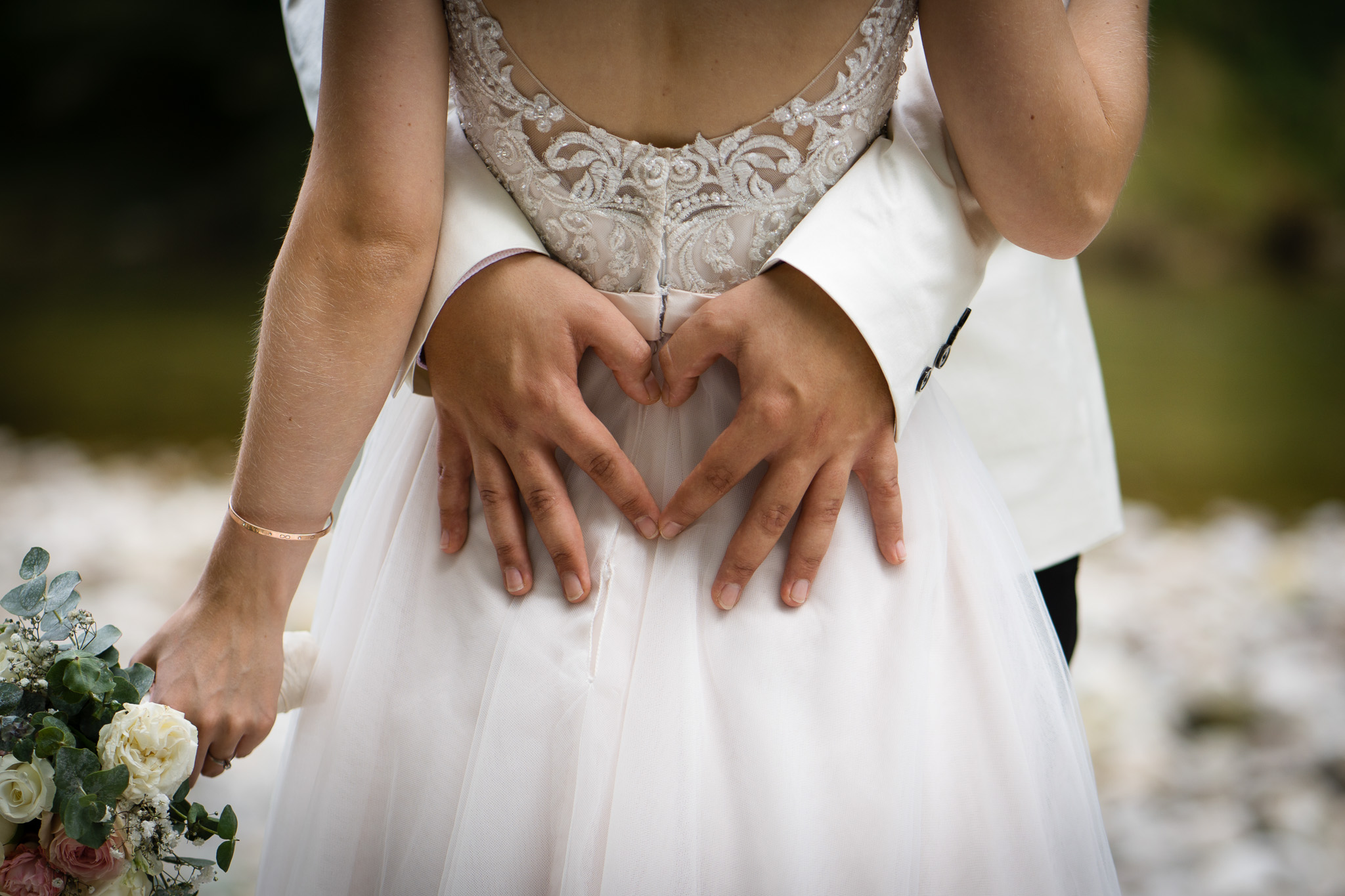 Eheringe und Herz aus Händen – Hochzeitsdetail | Lindl Photography Die Hände des Brautpaars formen ein Herz auf dem Brautkleid.