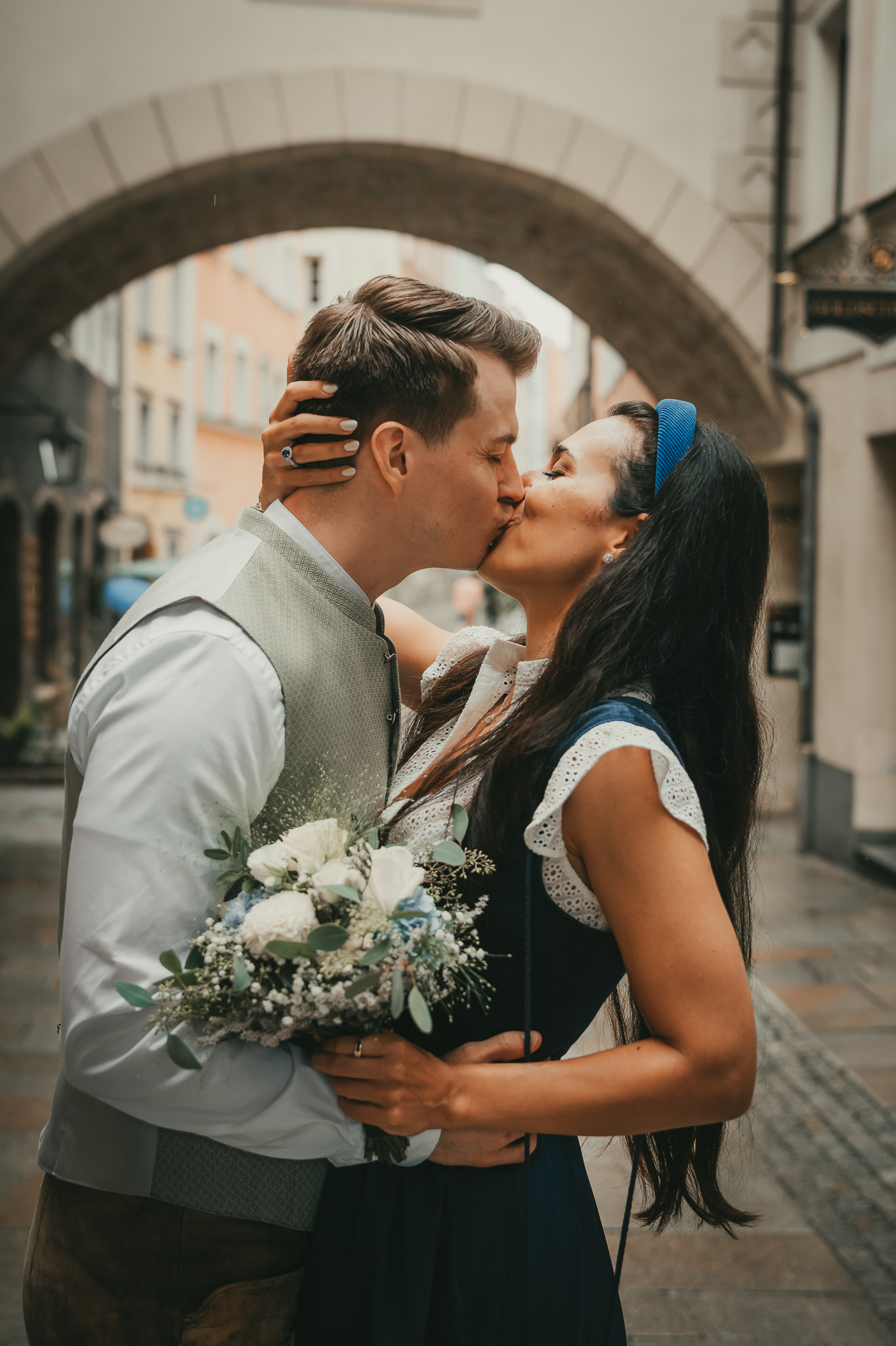 Brautpaar küsst sich nach der standesamtlichen Hochzeit vor einem historischen Torbogen in Burghausen