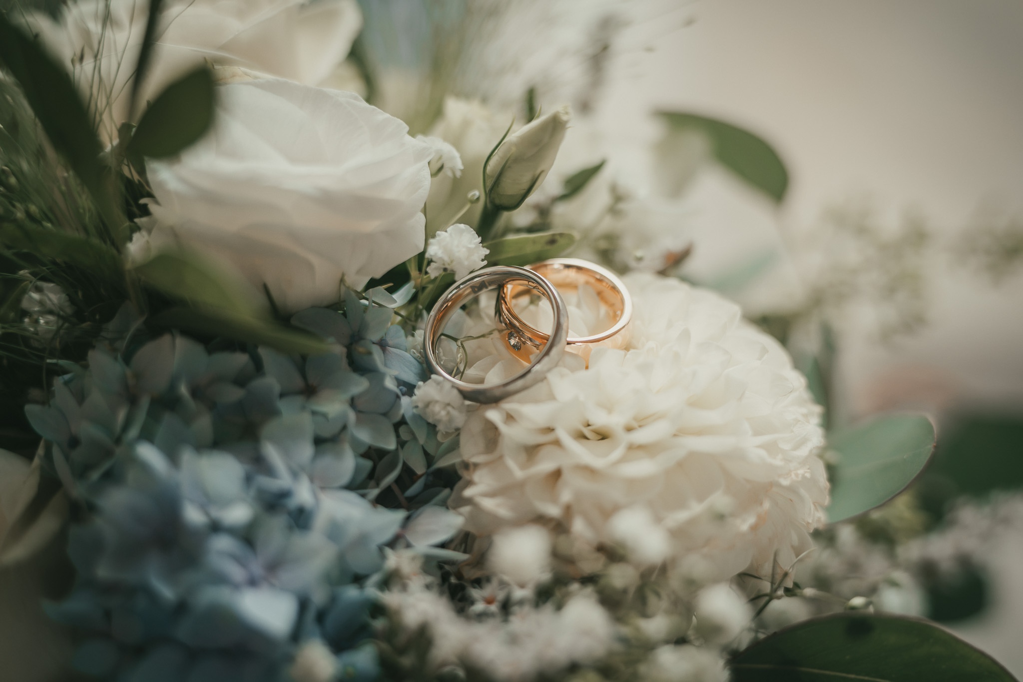 Eheringe auf dem Brautstrauß – Hochzeitsdetails | Lindl Photography Goldene Eheringe auf einem hellen Brautstrauß mit zarten Blüten