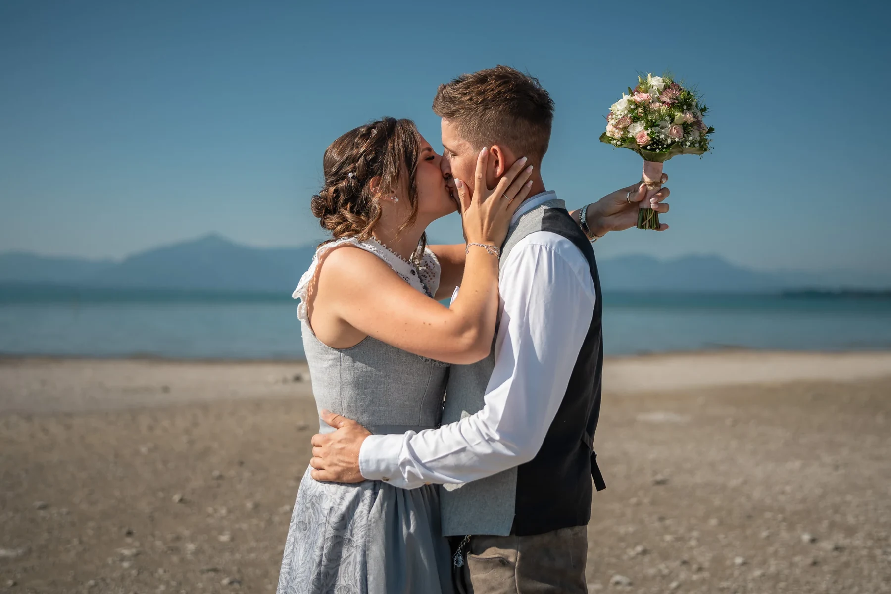 Brautpaar nach der standesamtlichen Hochzeit in Seebruck mit Chiemsee und Alpen im Hintergrund