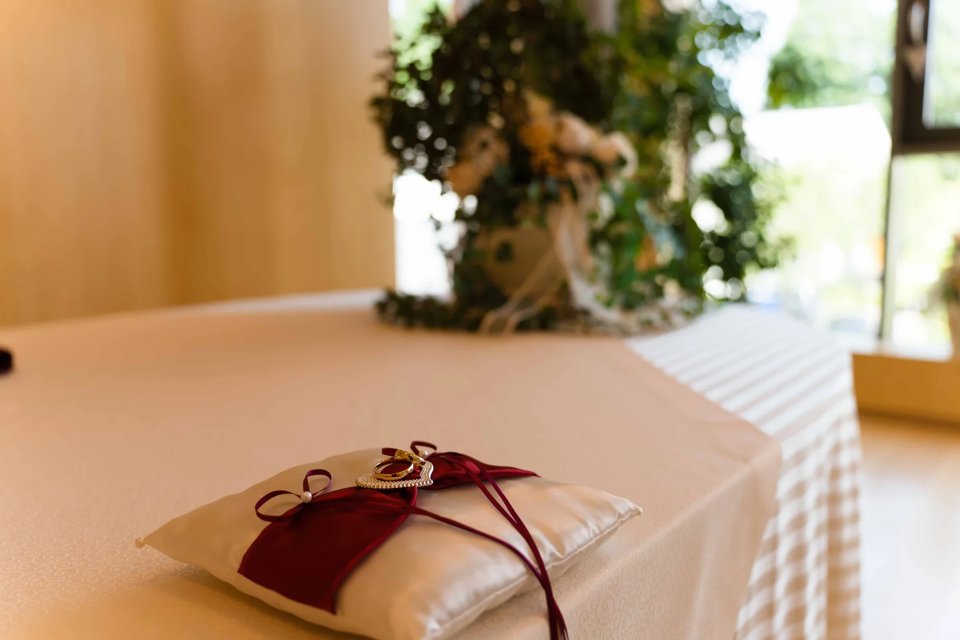 Ringkissen mit roten Schleifen auf einem festlich gedeckten Tisch