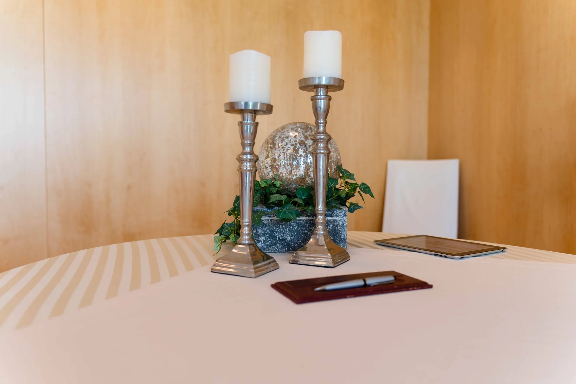 Festlich vorbereiteter Tisch mit Kerzen, Blumenschmuck und Unterlagen im Trauzimmer
