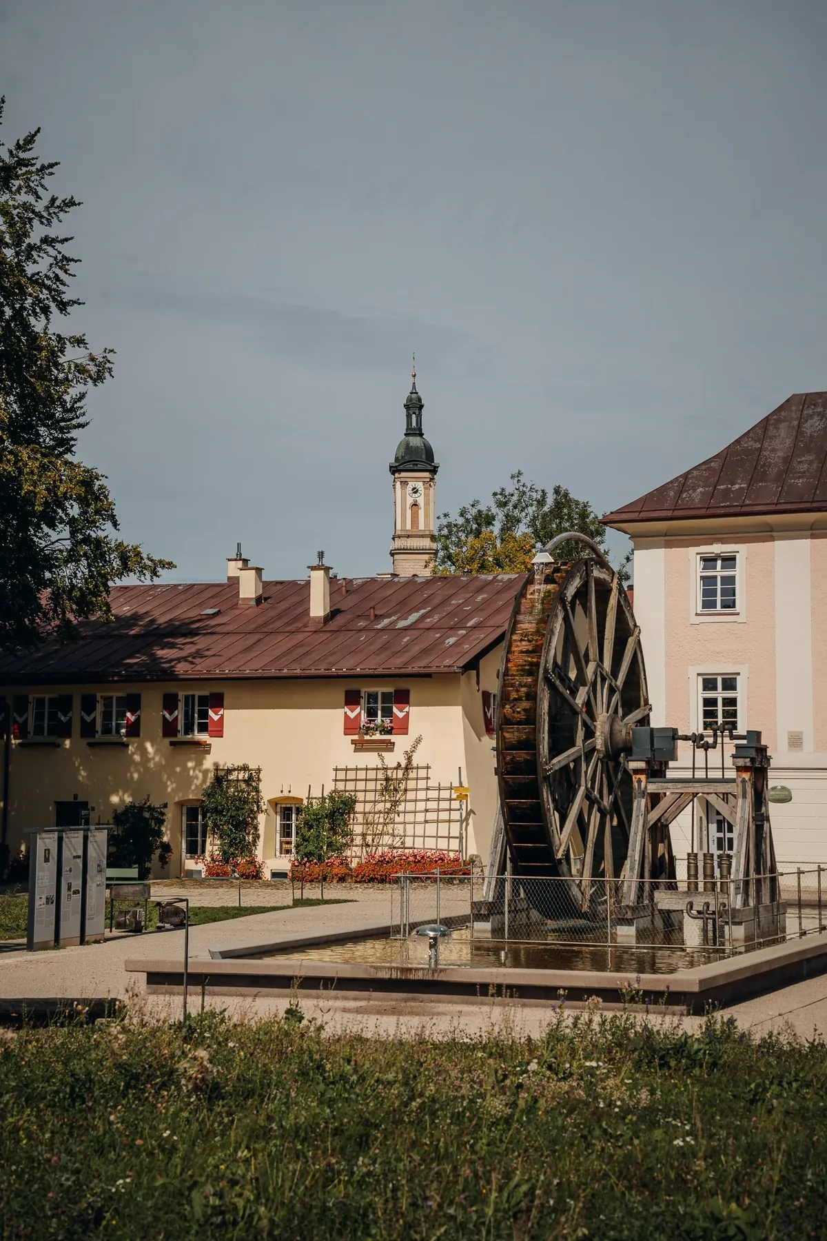Historisches Wasserrad im Salinenpark Traunstein mit Kirchturm im Hintergrund