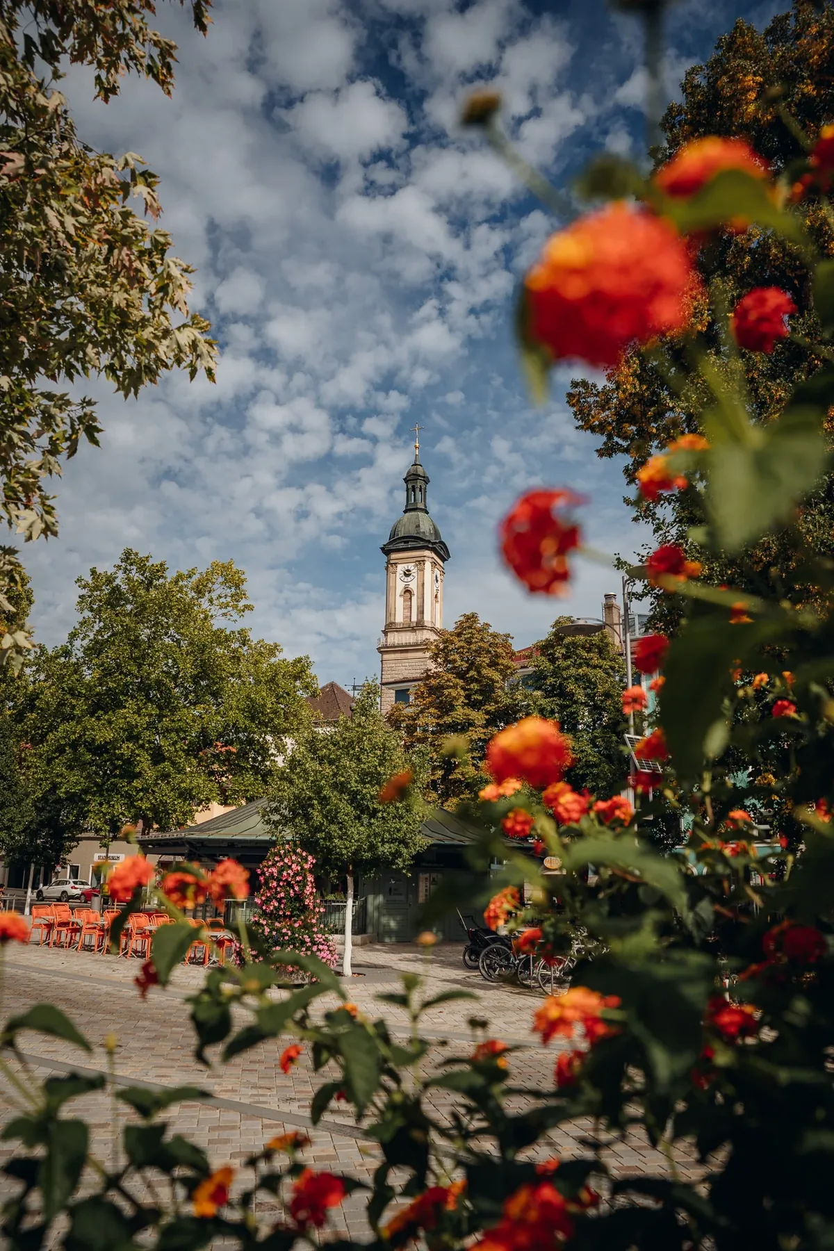 Blick durch Blumen auf den Kirchturm von St. Oswald in Traunstein